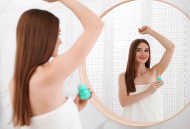 Güzel genç kadın banyoda duş sonra deodorant uygulamak
