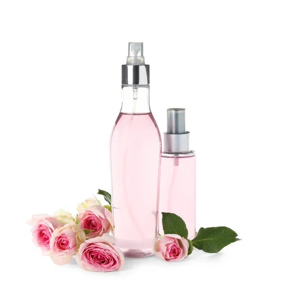 Garrafas de óleo essencial e rosas sobre fundo branco — Fotografia de Stock