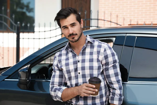 Atractivo joven con taza de café cerca de coche de lujo al aire libre — Foto de Stock
