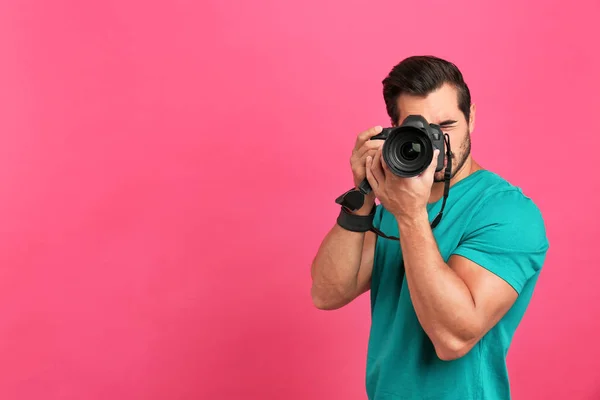 Młody profesjonalny fotograf robienia zdjęć na różowym tle. Miejsce na tekst — Zdjęcie stockowe