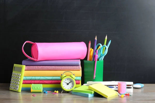 Verschiedene Schulschreibwaren auf Tisch neben Tafel — Stockfoto