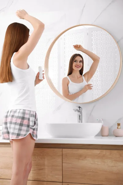 Bella giovane donna che applica il deodorante in bagno — Foto Stock