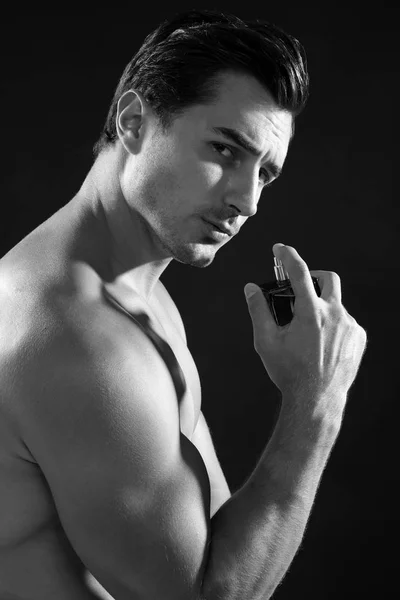 Handsome young man using perfume, black and white effect