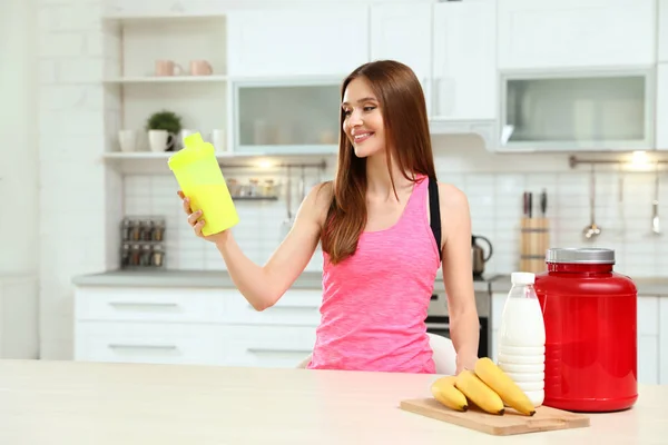 台所でタンパク質のボトルを持つ若い女性 — ストック写真