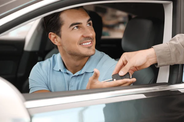 Jonge verkoper geven autosleutel naar klant in moderne autodealer, close-up — Stockfoto