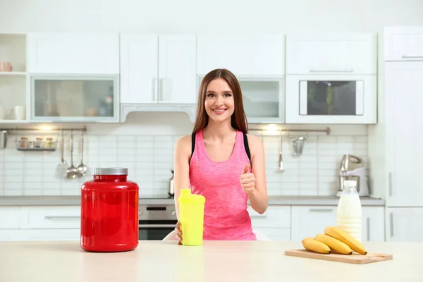 台所でタンパク質のボトルを持つ若い女性 — ストック写真