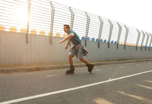 Handsome young man roller skating outdoors. Recreational activity