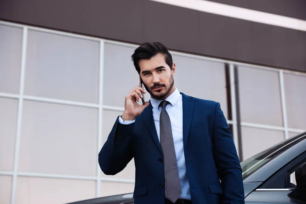 Attraente giovane uomo che parla al telefono vicino auto di lusso all'aperto — Foto Stock