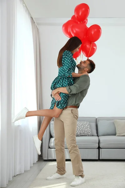 Junges Paar mit Luftballons zu Hause. Feier zum Valentinstag — Stockfoto