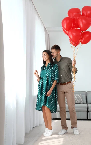 Junges Paar mit Luftballons zu Hause. Feier zum Valentinstag — Stockfoto