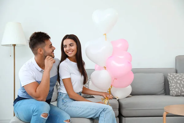 Junges Paar mit Luftballons zu Hause. Feier zum Valentinstag — Stockfoto