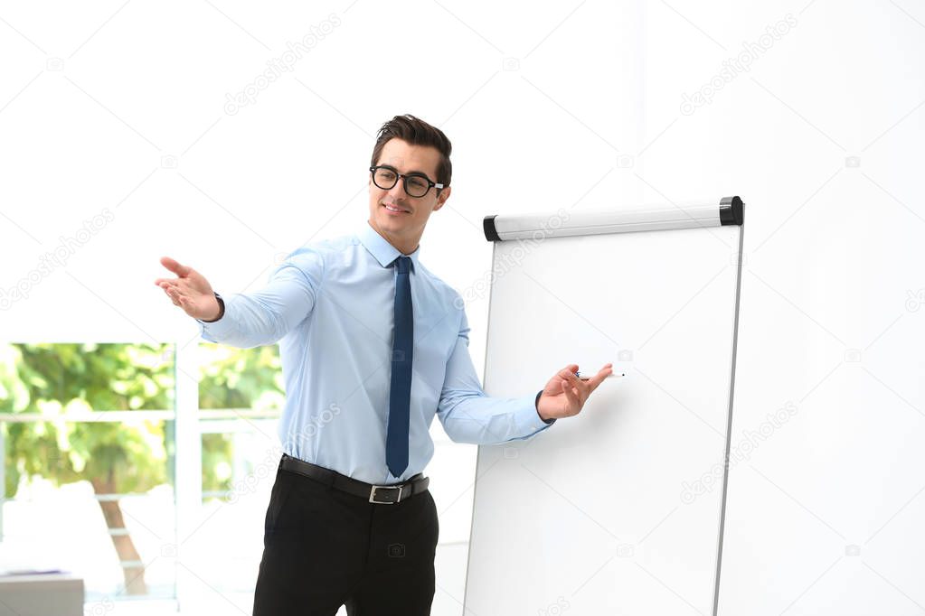 Professional business trainer near flip chart in office