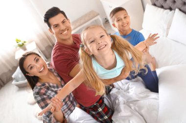 Çocuklu mutlu genç aile yatak odasında eğleniyor