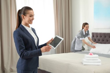 Otel odasında hizmetçi iş kontrol tablet ile Housekeeping yöneticisi. Metin için alan