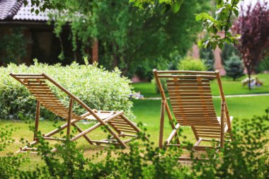 Güneşli günde güzel bahçede Ahşap şezlonglar