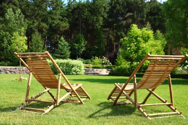 Güneşli günde güzel bahçede Ahşap şezlonglar