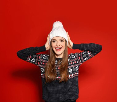 Kırmızı arka planda Noel süveteri giyen genç kadın