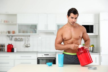 Genç gömleksiz atletik adam mutfakta protein shake hazırlanıyor, metin için alan