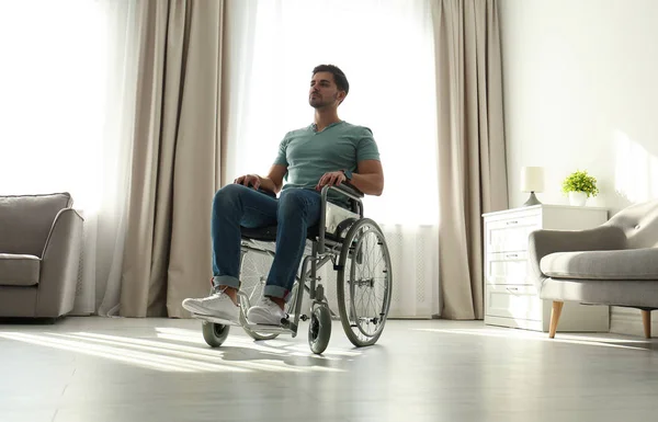 Молодой человек сидит в современном инвалидном кресле в помещении — стоковое фото