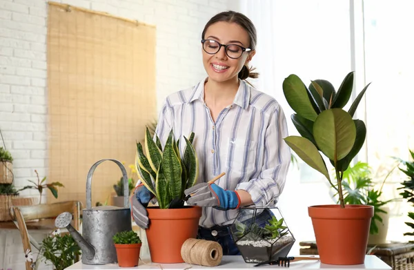 Ung kvinna som tar hand om krukväxter hemma — Stockfoto