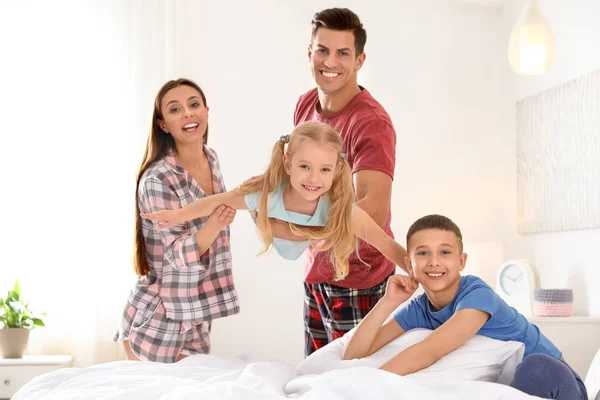 Szczęśliwa młoda rodzina z dziećmi bawiąc się w sypialni — Zdjęcie stockowe