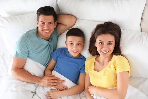 Portret van gelukkig jong gezin rusten in bed, boven uitzicht — Stockfoto