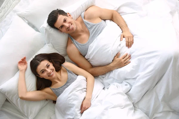 Adorável jovem casal descansando na cama grande, vista acima — Fotografia de Stock