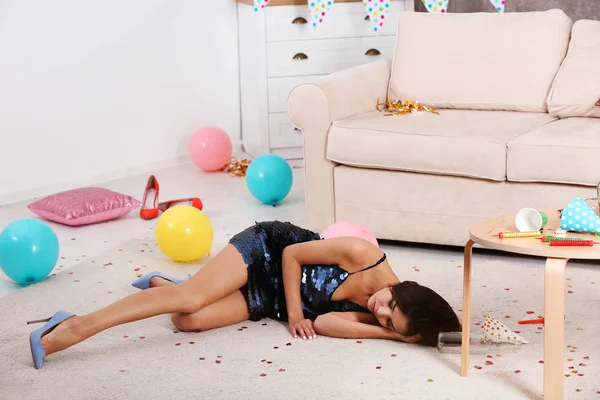 Молода жінка спить на підлозі в брудній кімнаті після вечірки — стокове фото