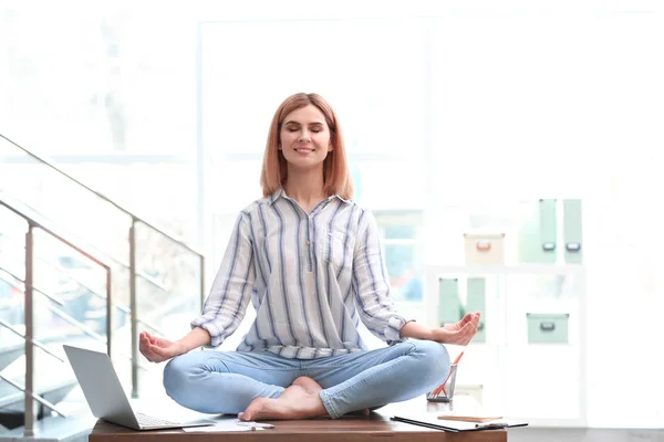 Красивая женщина медитирует на столе в офисе во время перерыва. Дзэн-йога — стоковое фото