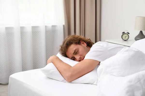 Красивый молодой человек спит на подушке дома. Время спать — стоковое фото