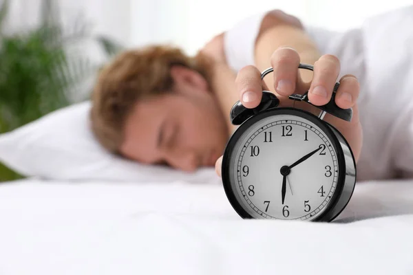 Sleepy man turning off alarm clock in morning, space for text. Bedtime — Stock Photo, Image