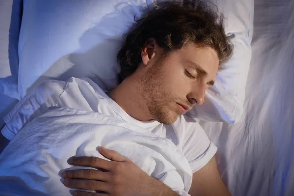 Beau jeune homme dormant sur un oreiller la nuit, vue de dessus. Au lit. — Photo