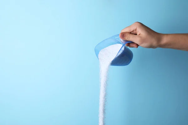 Woman pouring laundry detergent from measuring container against blue background, closeup. Space for text — Stock Photo, Image