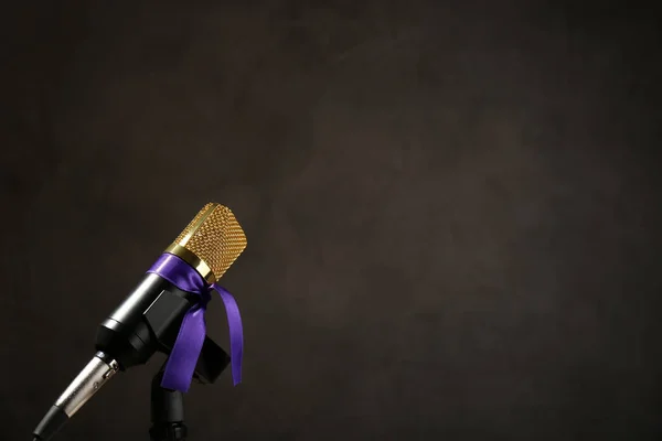 Mikrofon med lila medvetenhet band på mörk bakgrund, utrymme för text — Stockfoto