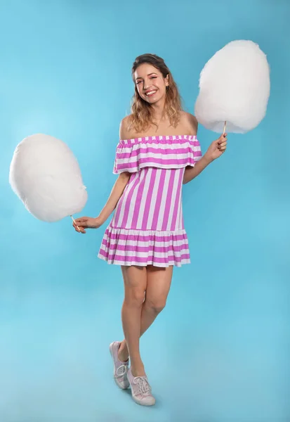 Ganzkörperporträt einer hübschen jungen Frau mit Zuckerwatte auf blauem Hintergrund — Stockfoto