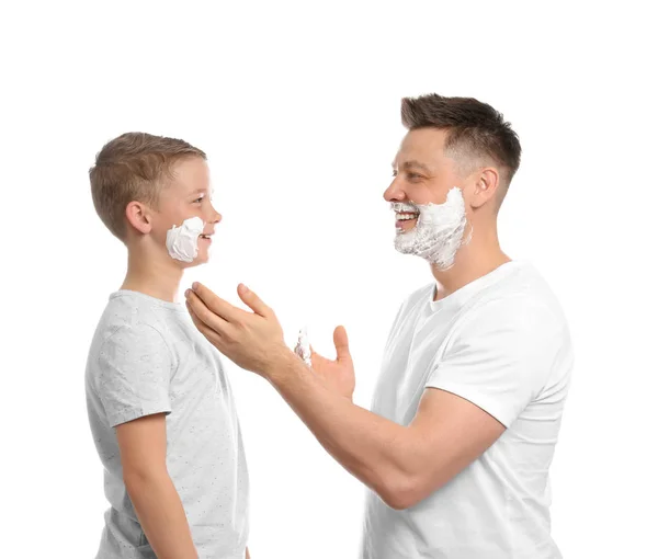 Papá aplicando espuma de afeitar en la cara del hijo, fondo blanco — Foto de Stock