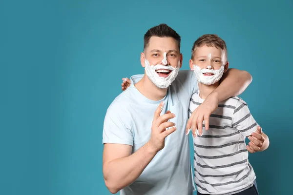 Szczęśliwy tata i syn z pianki do golenia na twarzach na niebieskim tle, miejsce na tekst — Zdjęcie stockowe