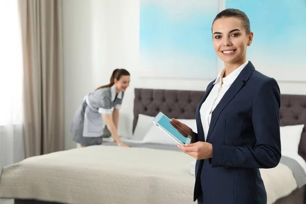 客房管理经理与平板电脑检查女佣在酒店房间的工作。文本空间 — 图库照片
