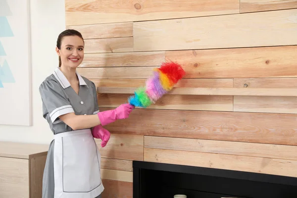 Jonge kamer meid afvegen stof met borstel in hotelkamers — Stockfoto