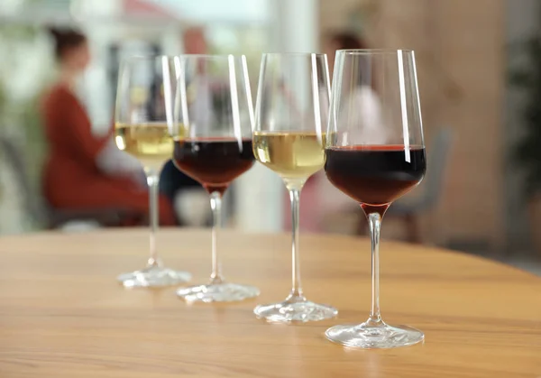 Glazen met verschillende wijnen op tafel tegen onscherpe achtergrond — Stockfoto