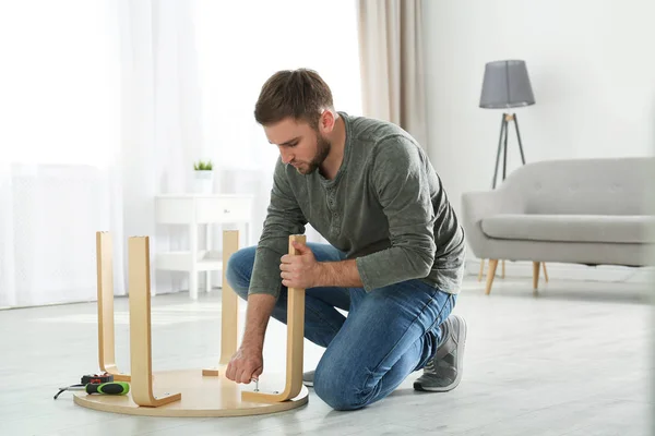 Joven trabajador reparando mesa en casa —  Fotos de Stock