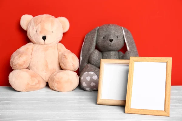 Peluches et cadres photo sur table sur fond rouge, espace pour le texte. Chambre enfant intérieur — Photo