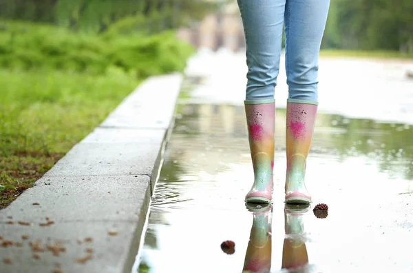 水たまりの中にゴムブーツを持つ女性、クローズアップ。雨天 — ストック写真