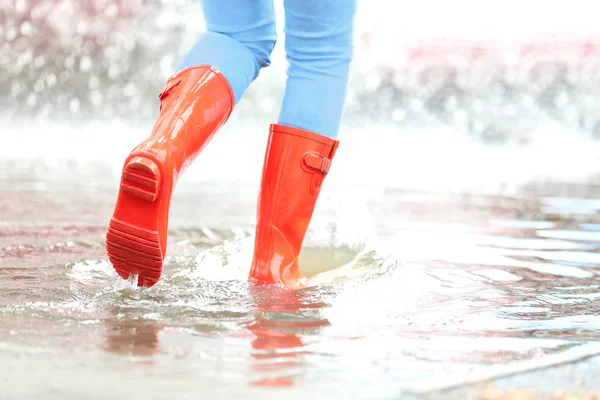 Kobieta z czerwonymi gumowymi butami w Puddle, zbliżenie. Deszczowa pogoda — Zdjęcie stockowe