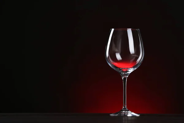 Copo de vinho vazio na mesa contra fundo escuro, espaço para texto — Fotografia de Stock