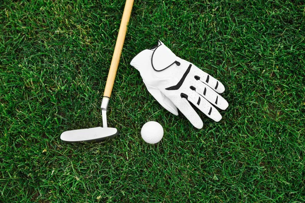 Golf kulübü, yeşil çim üzerinde top ve eldiven, düz yatıyordu — Stok fotoğraf