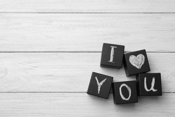Schwarze Würfel mit kreidegeschriebenen Worten Ich liebe dich auf weißem Holztisch, flach liegend. Raum für Text — Stockfoto