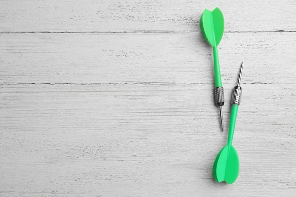 Flechas de dardo verde en la mesa de madera blanca, plano con espacio para el texto —  Fotos de Stock