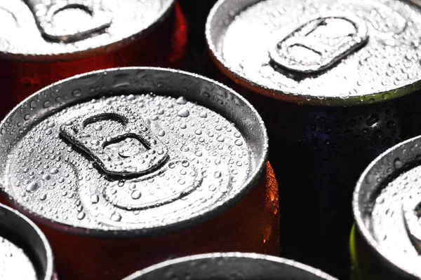 Aluminum cans of beverage covered with water drops as background, closeup