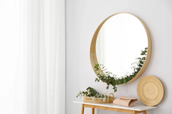 Miroir rond et table avec accessoires près du mur blanc. Design d'intérieur moderne — Photo